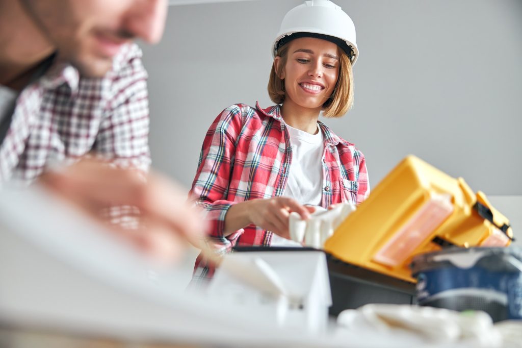 Smiling workwoman in a protective helmet and an engineer